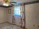 A bedroom featuring a ceiling fan and a window with floral curtains at 9510 Mark Twain Ln, Port Richey, FL 34668
