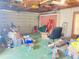 A cluttered garage with a roll up door and green flooring at 9510 Mark Twain Ln, Port Richey, FL 34668