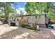Exterior view of an older mobile home featuring a yard, trees and aged siding at 10044 Oana St, New Port Richey, FL 34654