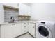 Well-lit laundry room featuring a modern washer, sleek cabinetry, granite countertops, and stylish tile backsplash at 1015 W Charter St, Tampa, FL 33602