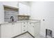 Laundry room featuring white cabinetry with dark hardware, granite counters and tiled backsplash at 1015 W Charter St, Tampa, FL 33602
