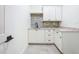 Well-lit laundry room featuring white cabinetry with dark hardware, granite counters and tiled backsplash at 1015 W Charter St, Tampa, FL 33602