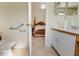 Bright bathroom showing a toilet with grab bars and a glimpse of the Primary bedroom at 11251 Pickford St, Spring Hill, FL 34609