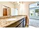 Bathroom with granite countertop, dual sinks, dark cabinets, and tiled shower at 11613 Sweet Tangerine Ln, Tampa, FL 33626
