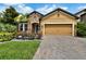 Charming home with brick paver driveway and two-car garage, complemented by lush landscaping at 11613 Sweet Tangerine Ln, Tampa, FL 33626