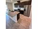 Modern kitchen with stainless appliances, dark cabinets, granite counters, and a large kitchen island with sink at 11634 Woodleaf Dr, Bradenton, FL 34211