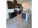 Kitchen featuring stainless steel appliances, dark cabinetry, granite countertops, and a functional kitchen island with sink at 11634 Woodleaf Dr, Bradenton, FL 34211