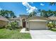 Inviting single-story home with a two-car garage, arched entryway, manicured lawn, and lush green landscaping at 11837 Derbyshire Dr, Tampa, FL 33626