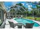 The screened-in pool area is surrounded by ample seating, lush landscaping, and clear blue skies at 11837 Derbyshire Dr, Tampa, FL 33626