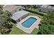 Aerial view of the property with a pool and enclosed patio, surrounded by lush greenery and a well-maintained yard at 1310 Rustlewood Dr, Brandon, FL 33510