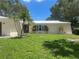 Inviting home featuring a well-manicured lawn, palm trees, and an arched entryway with glass front door at 13344 88Th Ave, Seminole, FL 33776