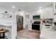 Modern kitchen with white cabinets, stainless steel appliances, breakfast bar with seating, and wood-look flooring at 13344 88Th Ave, Seminole, FL 33776