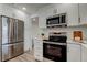 Modern kitchen with stainless steel appliances and white cabinets and wood look floor at 13344 88Th Ave, Seminole, FL 33776