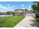 Two-story home with a lush green lawn, a long driveway leading to the attached garage, and a beautiful blue sky at 1712 Azalea Ct # B, Oldsmar, FL 34677