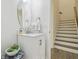 Stylish half bath with marble vanity and round mirror, located conveniently near the stairs at 17880 Althea Blue Pl, Lutz, FL 33558