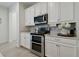 Well-equipped kitchen with stainless steel appliances, white cabinets, and stylish backsplash at 17880 Althea Blue Pl, Lutz, FL 33558