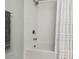 This modern bathtub and shower combination features elegant white tiling and contemporary fixtures for a clean, sophisticated look at 17880 Althea Blue Pl, Lutz, FL 33558