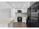 Updated kitchen features white cabinets, stainless steel appliances, a mosaic backsplash, and modern lighting at 201 Bedford St # 79, Sun City Center, FL 33573
