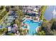 Aerial view of a large community pool and sun deck, surrounded by lush landscaping and trees at 201 Bedford St # 79, Sun City Center, FL 33573