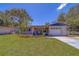 Charming home with a manicured lawn, complemented by yellow flora and a blue awning above the front door at 2123 Indigo Dr, Clearwater, FL 33763