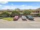 Exterior view of condo building featuring brick facade, mature trees, and parking spaces at 2192 Swedish Dr # 26, Clearwater, FL 33763