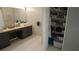 Bathroom showcasing double sinks, a neutral countertop, dark cabinets, and a closet at 25435 Bruford Blvd, Land O Lakes, FL 34639