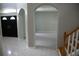 Foyer with gray tile flooring, staircase with wood trim, and decorative archways leading to the living spaces at 25435 Bruford Blvd, Land O Lakes, FL 34639