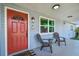 Close-up of a charming front porch with seating and a vibrant red front door at 3809 N 14Th St, Tampa, FL 33603