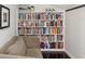 A white bookshelf completely filled with colorful books next to a neutral couch at 422 Cypress View Dr, Oldsmar, FL 34677