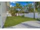 Well-manicured backyard with lush green grass, a white fence, and mature trees, ideal for outdoor enjoyment at 4495 Clearwater Harbor S Dr, Largo, FL 33770