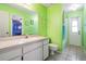 Green bathroom featuring a single sink vanity, toilet, mirror, and walk-in shower at 5423 Windbrush Dr, Tampa, FL 33625