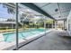 Enclosed pool with concrete patio, screen enclosure, and lush landscaping at 5423 Windbrush Dr, Tampa, FL 33625