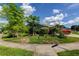 Landscaped front yard featuring a variety of trees and shrubs, complemented by a charming neighborhood sign at 604 Knollwood Dr, Largo, FL 33770
