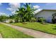 Well-manicured front yard with lush grass, tropical foliage, and a paved walkway leading to the entrance at 604 Knollwood Dr, Largo, FL 33770