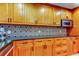 Bright kitchen features custom wood cabinets, stainless steel microwave, a decorative backsplash, and black countertops at 604 Knollwood Dr, Largo, FL 33770