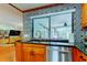 Kitchen sink features stainless steel appliances, brass faucet, custom cabinets, black countertops, and a decorative tiled wall at 604 Knollwood Dr, Largo, FL 33770