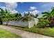 Charming side yard featuring a white picket fence covered in vines and lush tropical landscaping at 604 Knollwood Dr, Largo, FL 33770