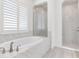 Bright bathroom with a soaking tub, a walk-in shower with marble surround and shuttered window at 6057 Marsh Trail Dr, Odessa, FL 33556