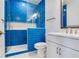 Modern bathroom with blue tiles, a glass door shower, and white cabinets at 6057 Marsh Trail Dr, Odessa, FL 33556