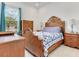 Classic bedroom design with wood furniture, a quilt bedspread, and natural light from the window at 6057 Marsh Trail Dr, Odessa, FL 33556