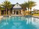 Beautiful community pool surrounded by palm trees and yellow umbrellas and lounge chairs at 6057 Marsh Trail Dr, Odessa, FL 33556