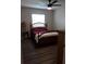 Comfortable bedroom with wood-look floors, ceiling fan, and a cozy bed with warm red linens at 702 Cypress Pl, Sun City Center, FL 33573