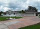 Inviting single-story home with a spacious driveway, mature palm trees, and a well-manicured front lawn at 702 Cypress Pl, Sun City Center, FL 33573