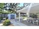 Inviting back patio with outdoor dining set, lounge chairs, storage shed, and mature trees for serene outdoor living at 7427 Banner St, New Port Richey, FL 34653