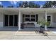 Charming front porch with seating area, decorative plants and gray painted brick facade at 7427 Banner St, New Port Richey, FL 34653
