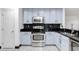 Updated kitchen features stainless steel appliances, light blue cabinets, and dark countertops with mosaic backsplash at 7515 Dragon Fly Loop, Gibsonton, FL 33534