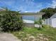 Home featuring mature landscaping, a window with an accordion shade, and a white fence at 9505 Marlinton Ln, Port Richey, FL 34668