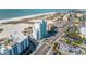 Expansive aerial view showcasing the condo building, the adjacent beach, and the lively street below at 11000 Gulf Blvd # 1004, Treasure Island, FL 33706