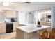 Bright kitchen featuring light wood cabinets, a U-shaped marble countertop, and modern appliances at 11000 Gulf Blvd # 1004, Treasure Island, FL 33706