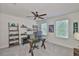 Bright home office with a sleek glass desk, ceiling fan, and plenty of natural light from the window at 11044 Spring Point Cir, Riverview, FL 33579